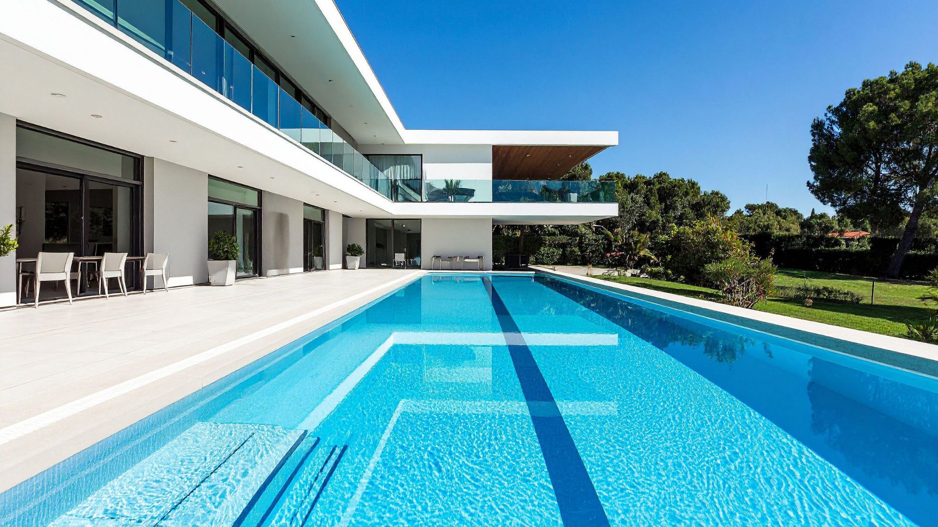 Modern white house with blue swimming pool and glass balconies