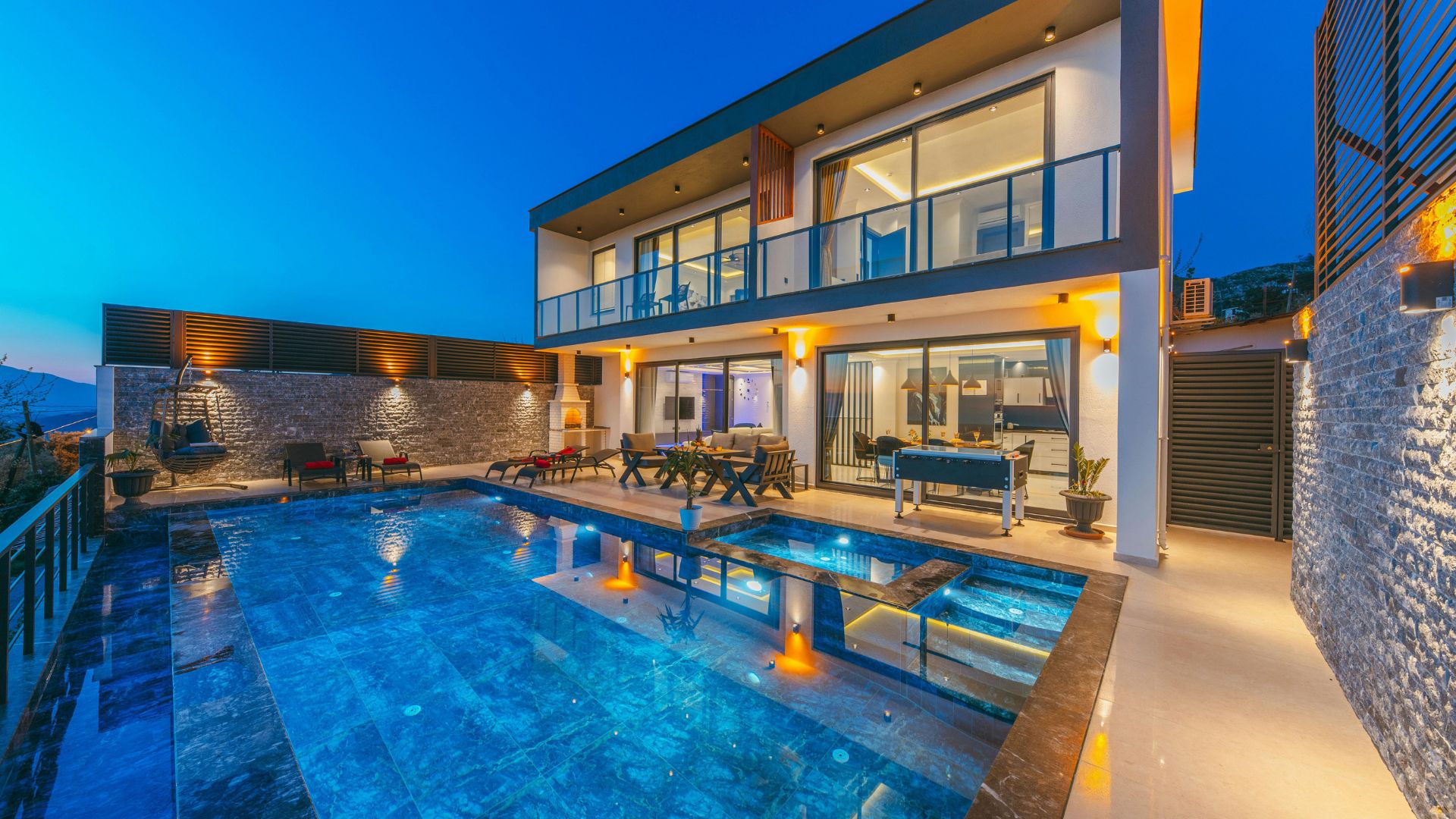 Luxurious modern villa with pool at night, glowing with warm lights