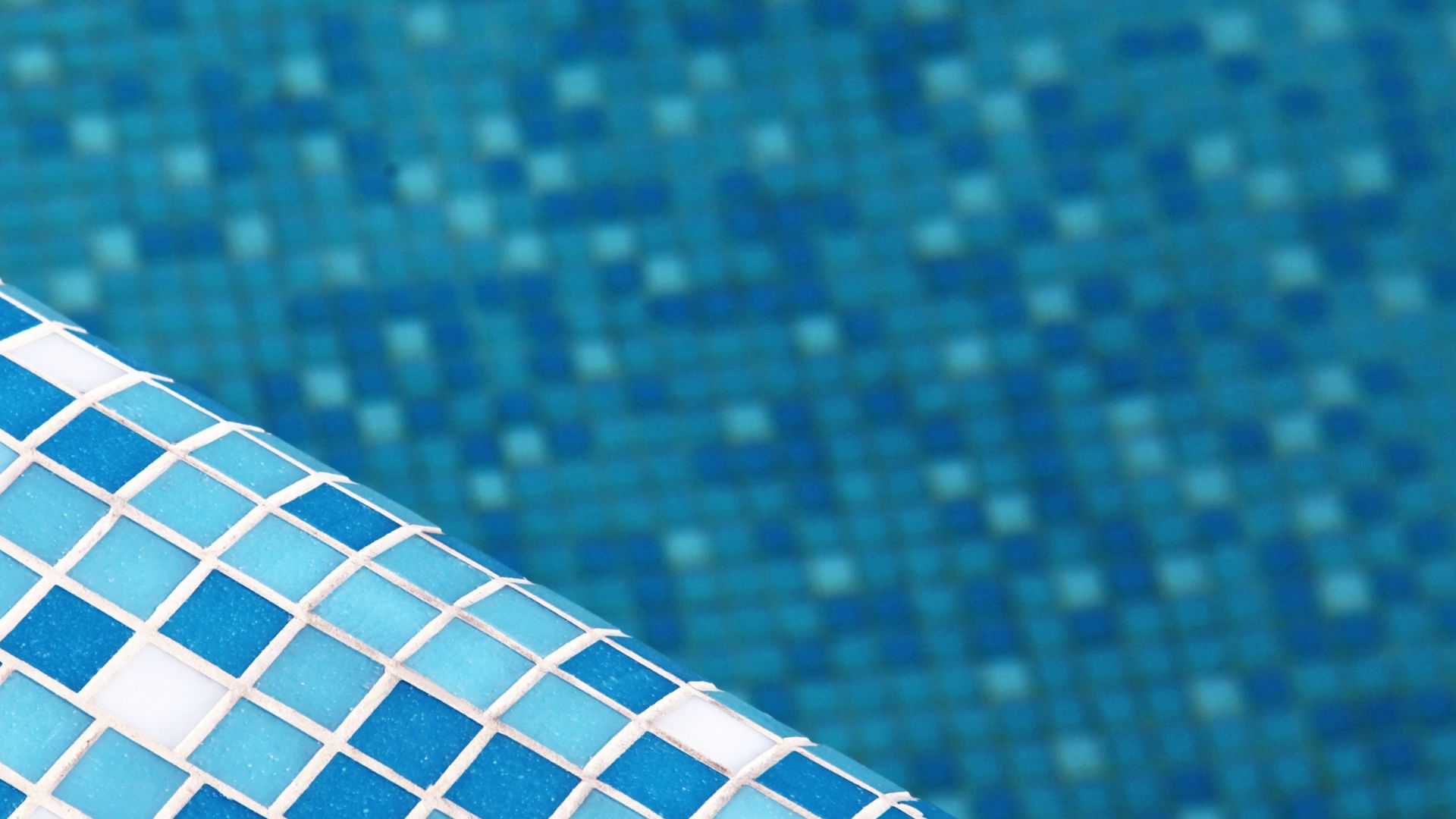 Blue swimming pool tiles with white grout, close-up view
