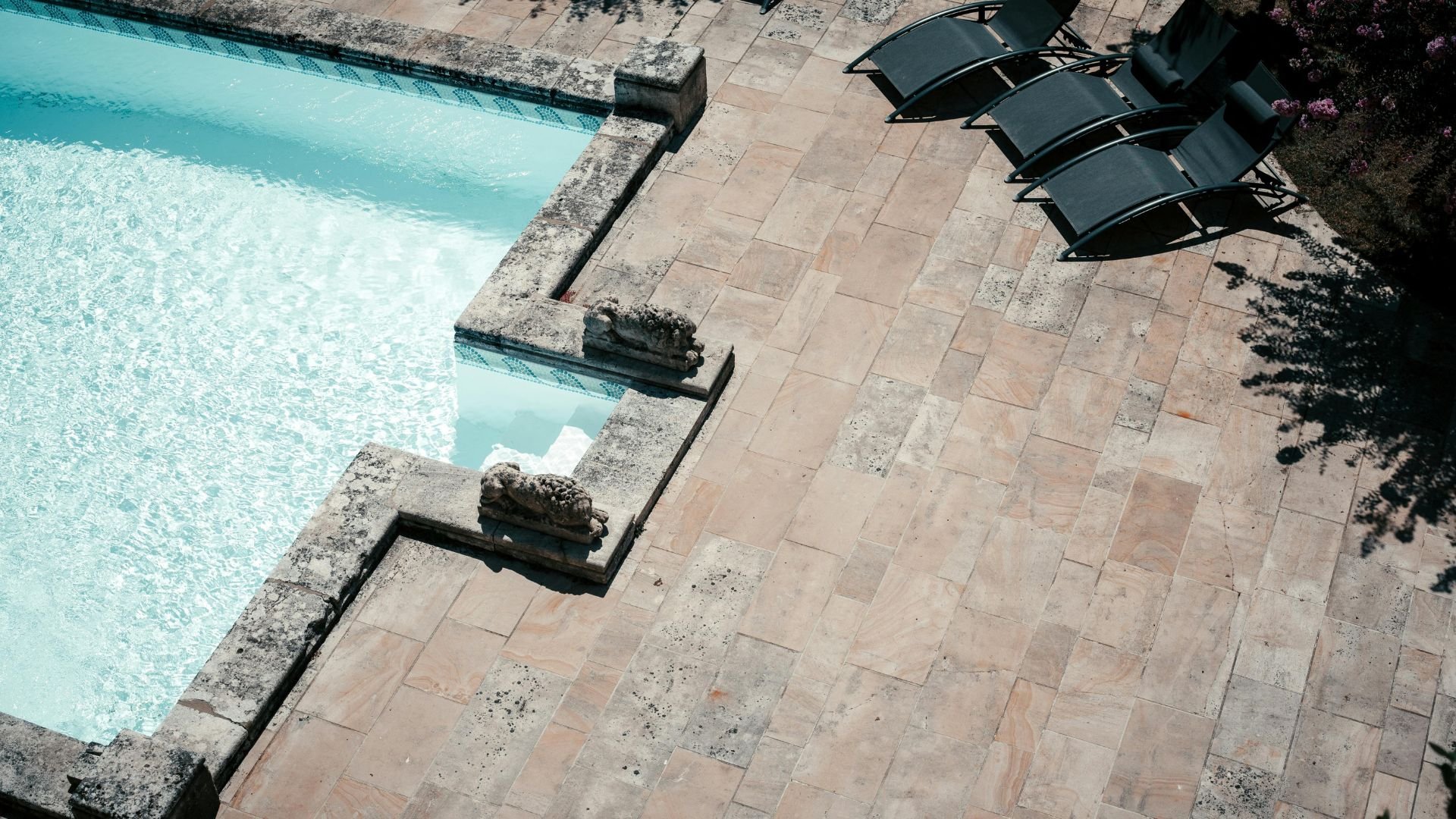 Turquoise pool with stone deck and lounge chairs, geometric design